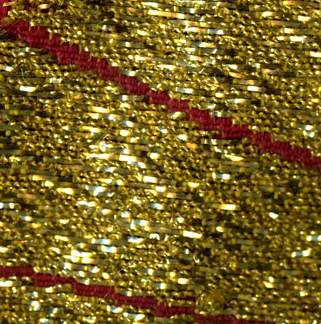 close up of cloth of gold showing red skein and golden threads glittering