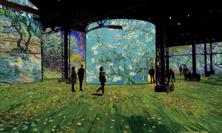 L’Atelier des Lumières exhibition of van Gogh showing people in enclosed space looking at images from Van Gogh's paintings on walls, ceiling and floor