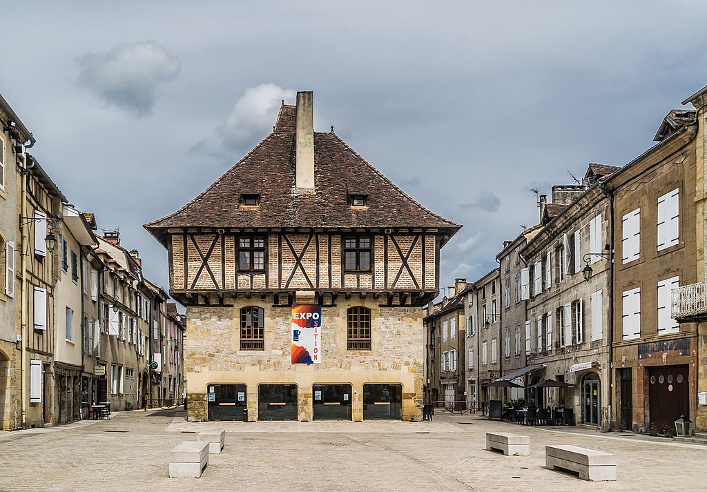 Saint-Cere old town showing half-timbered upper storey of town hall and stone underneath with arcades at bottom with two street running away into distance on either side