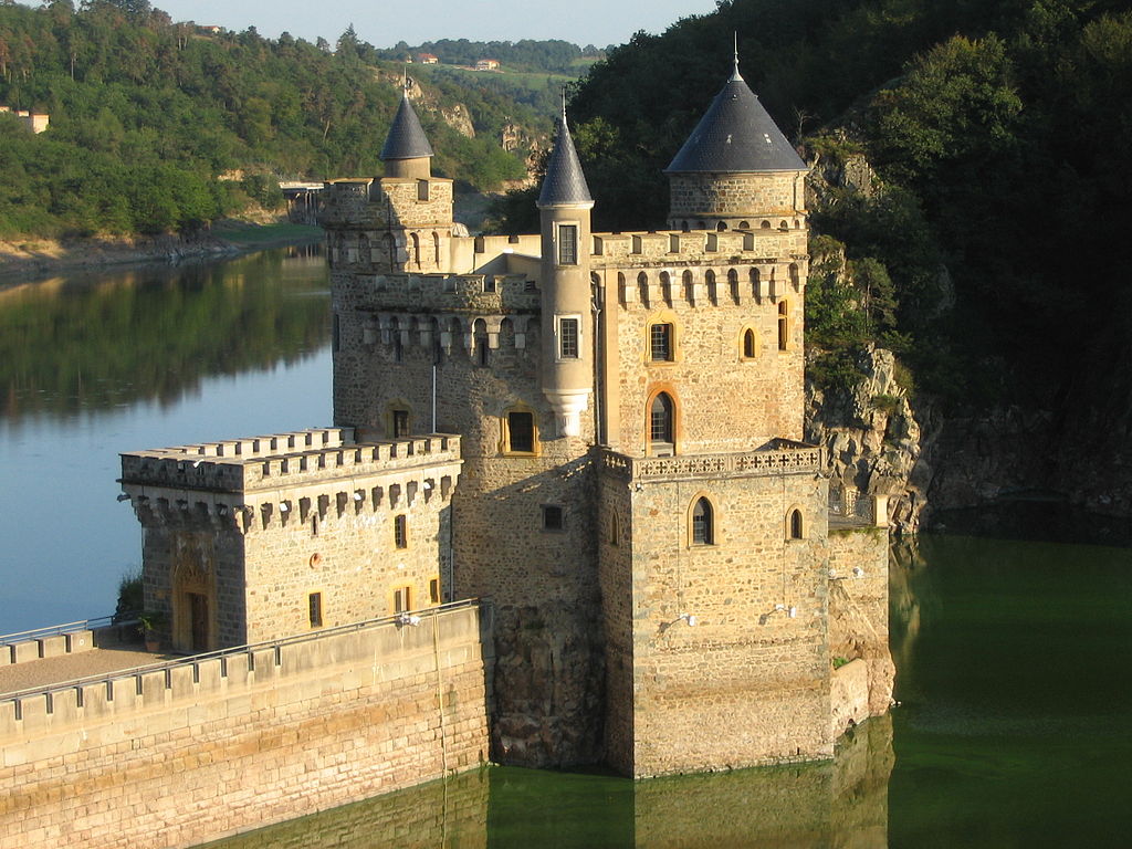 Château de la Roche stone building and walls and stone bridge standing in the Loire river with hills behind