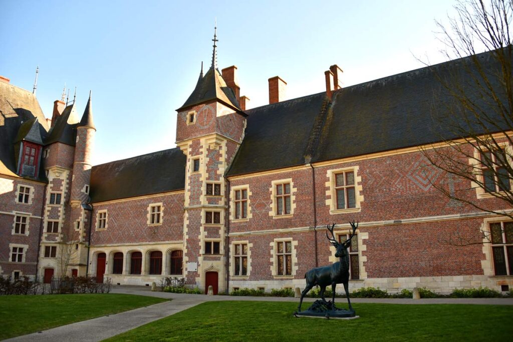 Museum of La Chasse (Hunting) at Gien. Old red brick 2-storey very large building with tower in middle and green grass in front