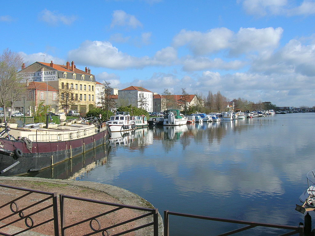 Port of Roanne from land showing water on right and quays with boats drawn up and houses behind
