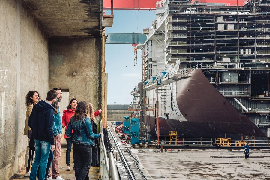 People on left on industrial platform looking at a ship being constructed at Chantiers navals St Nazaire
