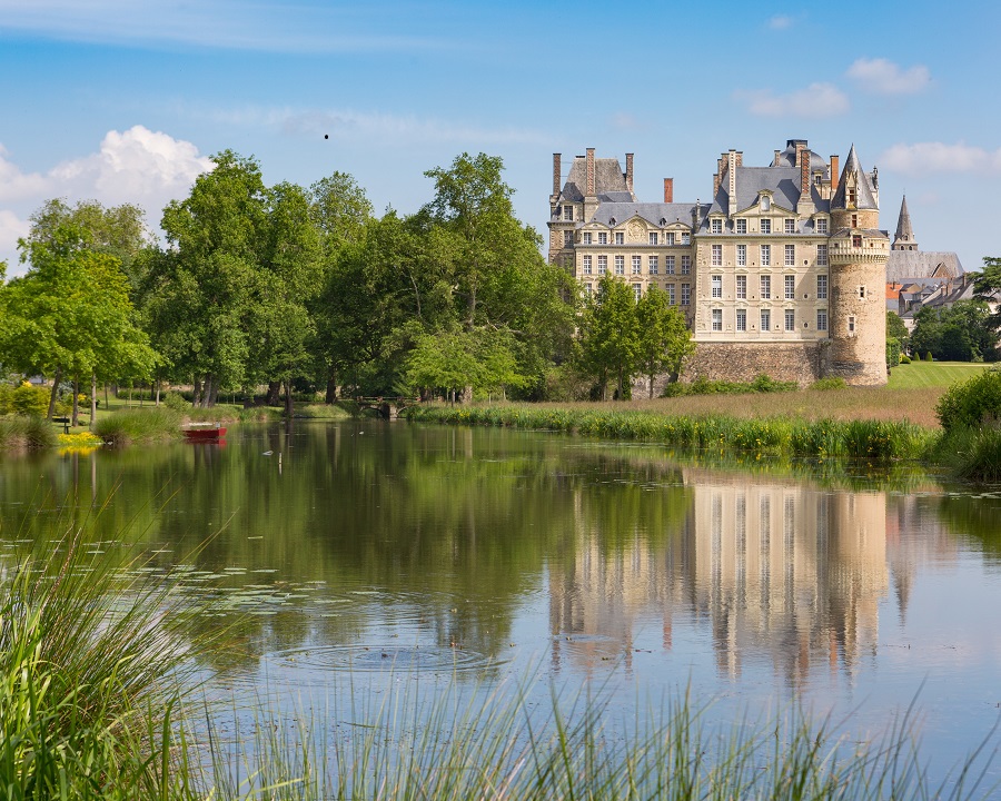 Château deBrissac Loire Valley with big lake in front and trees to left and far away 7-storey chateau reflected in waters