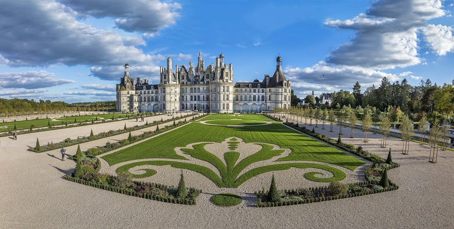 Chateau de chambord Loire Valley from long distance with gardens with flower beds shaped like fleur de lys in front of huge Renaissance building