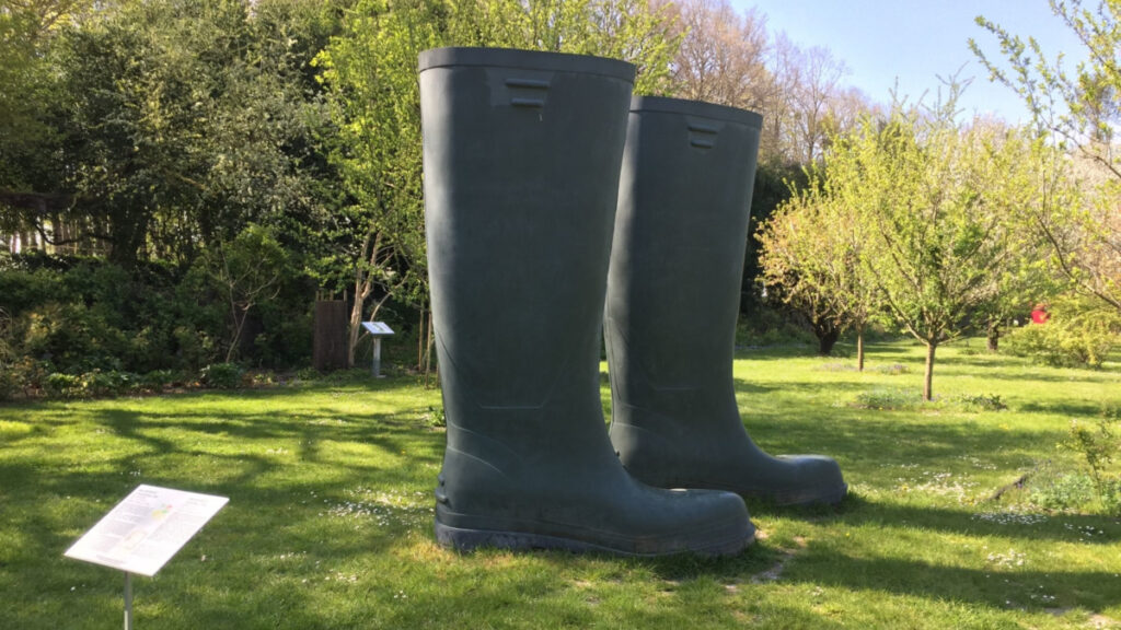 Château de Rivau Loire Valley gardens. Huge pair of wellington boots on lawn with trees in background, contemporary art