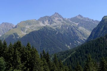 Long view of Belledone range in Isere showing dark woods, rolling muntains behind and blue sky in summer