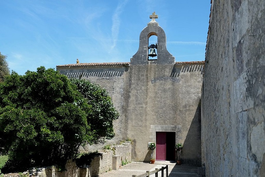 St Martin church on Ile d'Aix with high windowless walls of church with bell tower in middle and long wall of grey stone to right