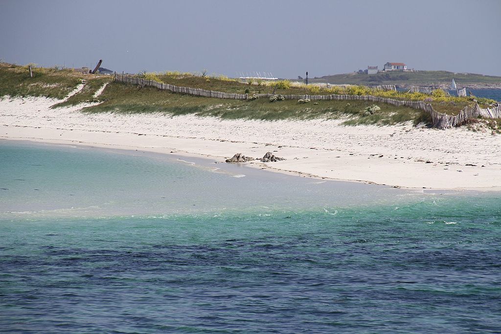 Glenan Brittany islands view from sea blue at front then turquoise then lapping at white sandy beach with small dunes behind covered in grass