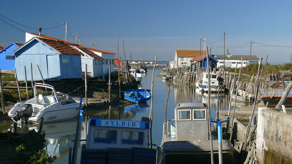 Ile d'Oleron island France showing narrow channel from sea runing into foreground harbour with boats and houses on banks of either isde