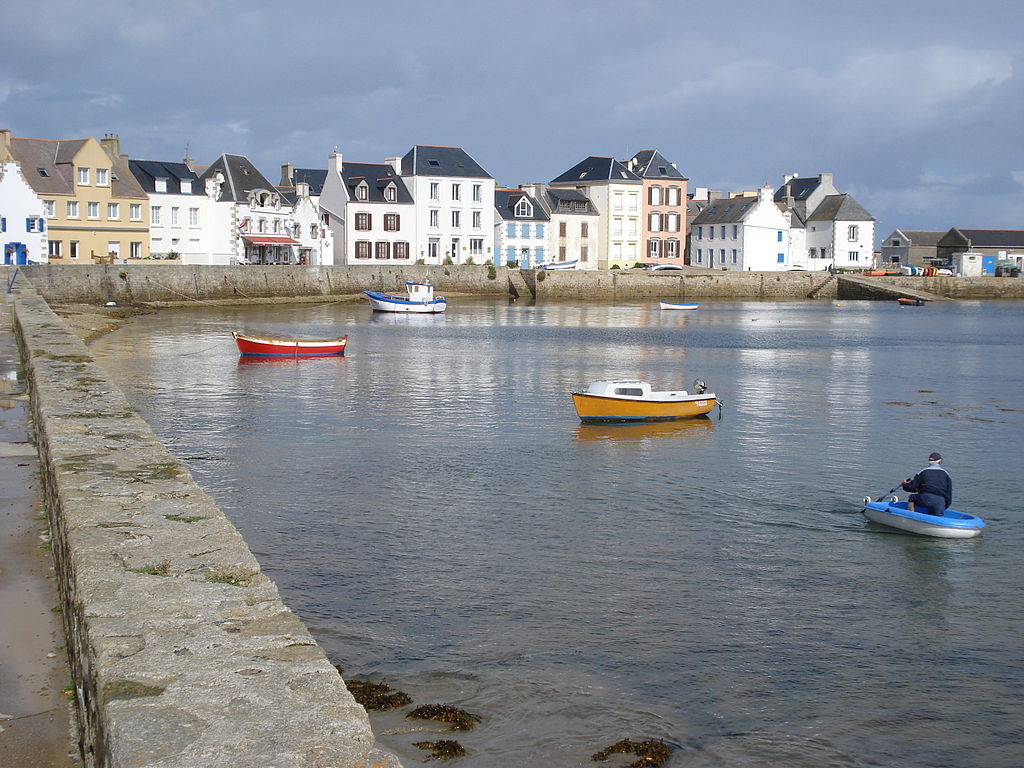 Port at Ile de Sein Brittany islands with view from end of stone quay looking towards tranquil port with boats bobbing and white houses in background