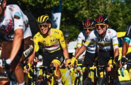 Tadej riding with his team and holding hand of one at tour de france 2021 final
