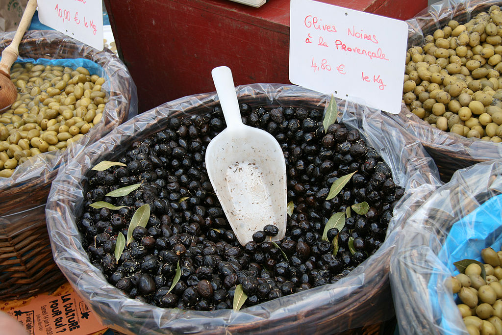 apt market Provence sack of black olives with small silver trowel and green leaves
