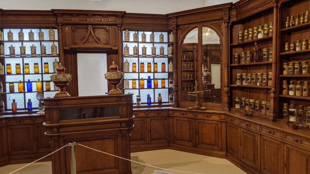 Bauge 19th century apothecary with solid wooden shelves and cupboards stacked with medicines