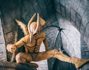 Gargoyle at Parc Asterix crouching on wall with one leg outstretched and wings behind