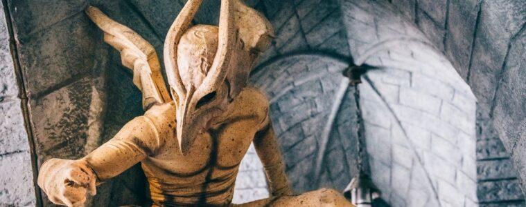 Gargoyle at Parc Asterix crouching on wall with one leg outstretched and wings behind
