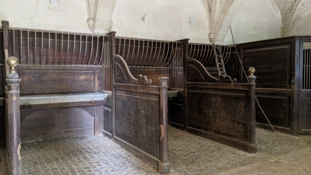 Château du Lude stables emptyof horses but showing cobbled floors, stalls with wooden dividers