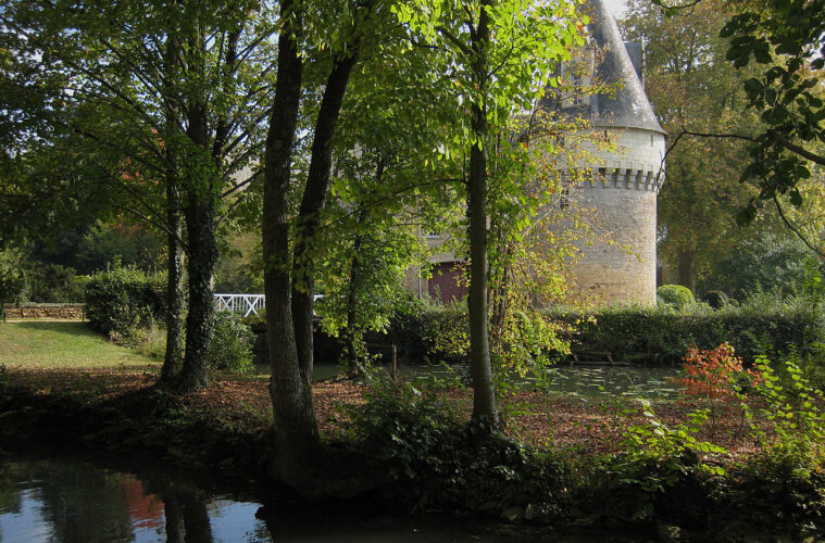 Chateau de Bazouges with trees and water in front partly shading a beautiful round stone tower with conical roof