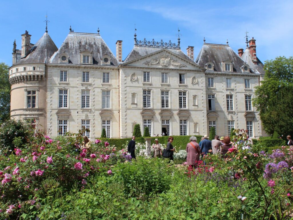 Château du Lude Loir Valley Rose Garden withpeople among rose trees and green bushes in front of elegant 18th century classical facade