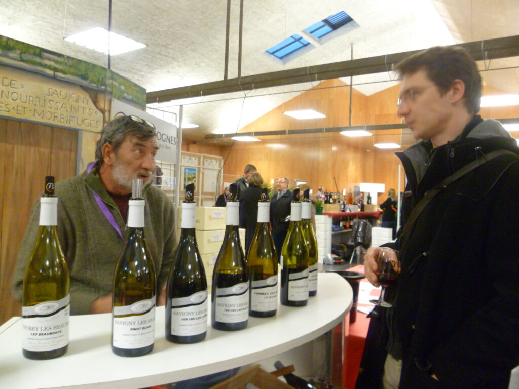 Calais Salon des vignerons with man behind row of bottles and spectator with glass in hand