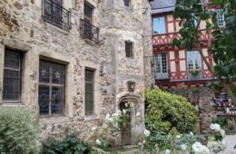 Le Mans bed and breakfast showing large stone building with garden of white roses in front andhalf-timbered building behind