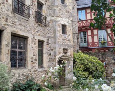 Le Mans bed and breakfast showing large stone building with garden of white roses in front andhalf-timbered building behind