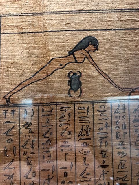 Egyptian hieroglyphs on bottom of parchment, with lady leading on top and scarab between