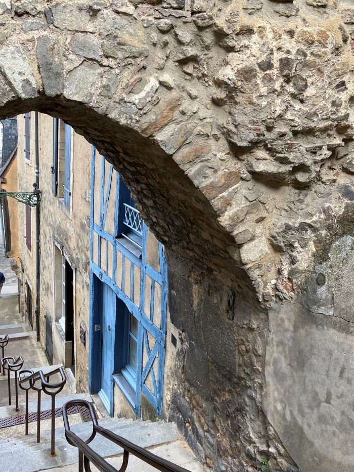 Old Le Mans looking down through stone arch at steep steps with old houses in stone and half-timbered painted blue wood