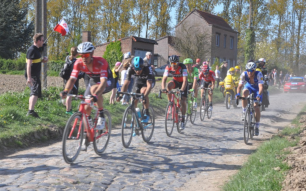 Paris-roubaix April cycle race with cyclists racing over cobbled roads and spectators waving flags