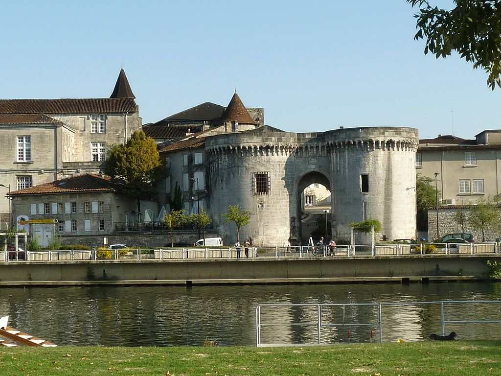 Cognac from the river charente showing old walls and gateway and quay along the river