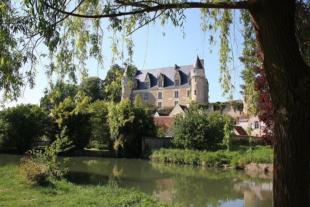Montrésor chateau on opposite bank with lake in front. Gracious stone renaissance chateau with steep roof and little towers