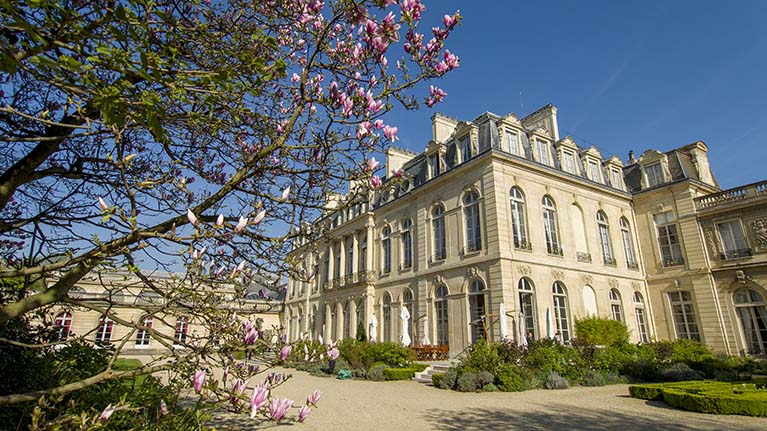 Elysee Palace from garden behind pink magnolia looking at gracious neo classical building from corner