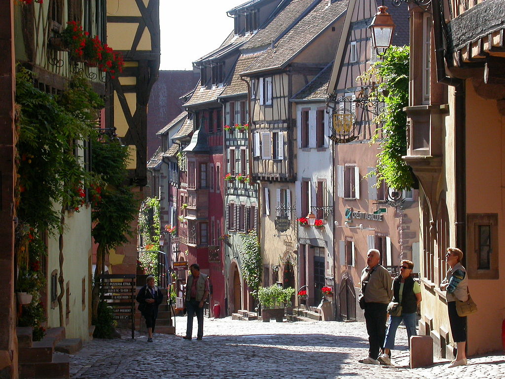 riquewihr in Alsace. Old street with high half timbered and brightly painted houses and people walking down