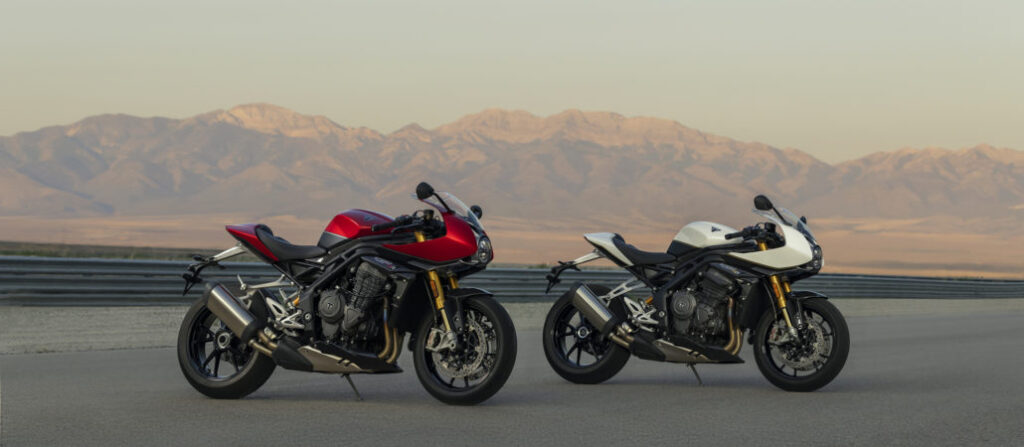 New Speed Triple 1200 RR Triumph on display at the Bol d'Or 2022 with two super motorbikes parked on land with mountinas behind, one red, one black