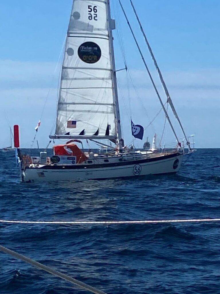 Golden Globe sailor in boat at start with one sail up, taken sideways on