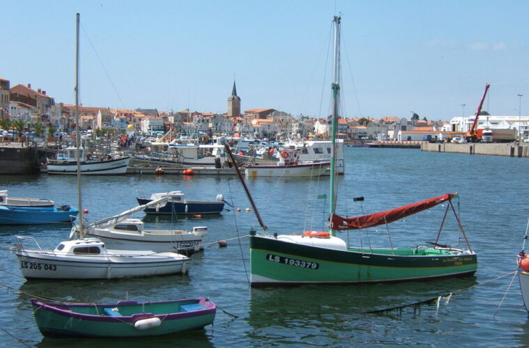 Les Sables d’Olonne port with small boats in front and old tow ehind with high church tower