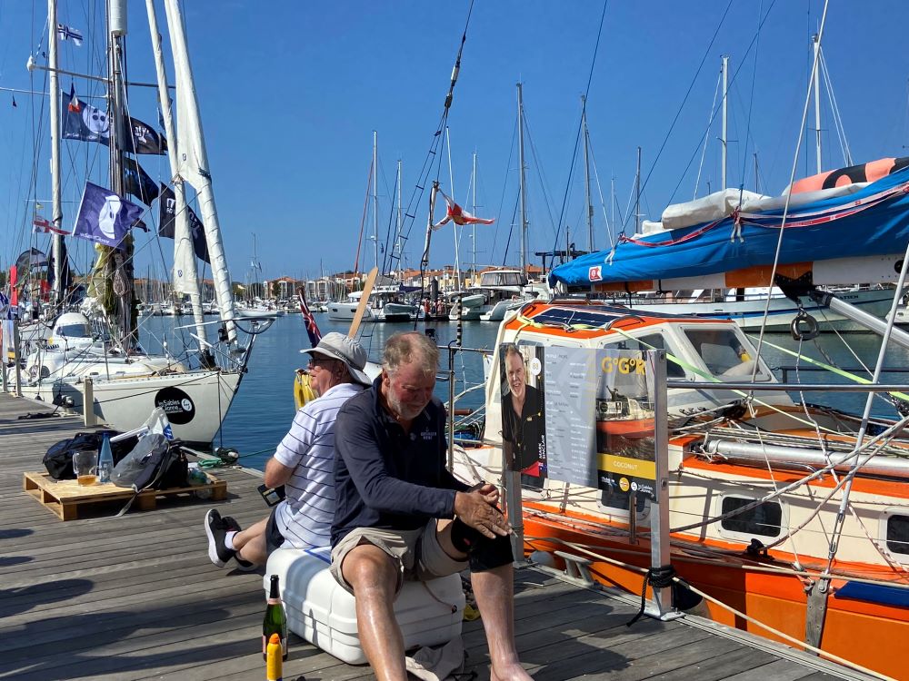 Golden Globe race start Mark Sinclair strapping knee beside boat