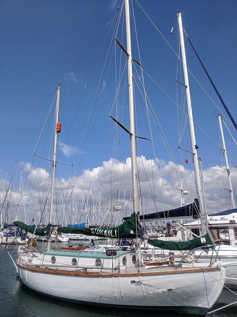Suhaili boat of Robin Knox-Johnston side on showing three masted ketch against clouds and blue sky