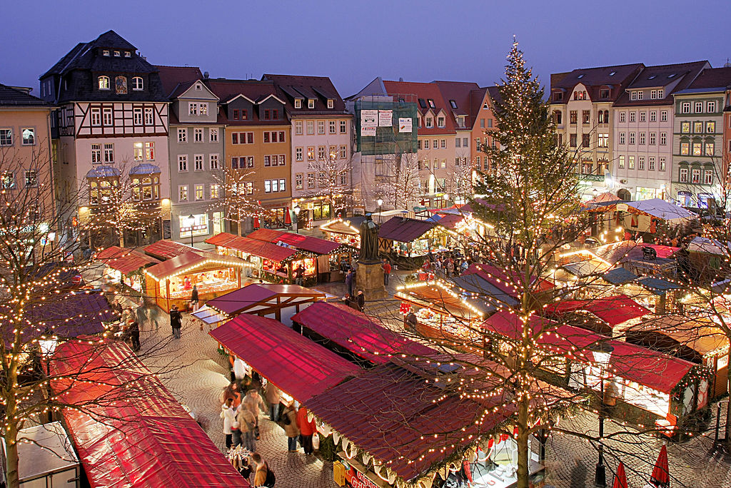 View from above of Metz Christmas market in square with brightly lit chalets in square surrounded by old houses