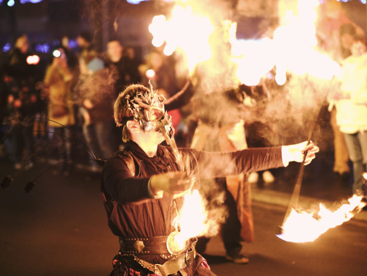 Nightime with man breathing fire on procession in streets for La Sainte Barbe