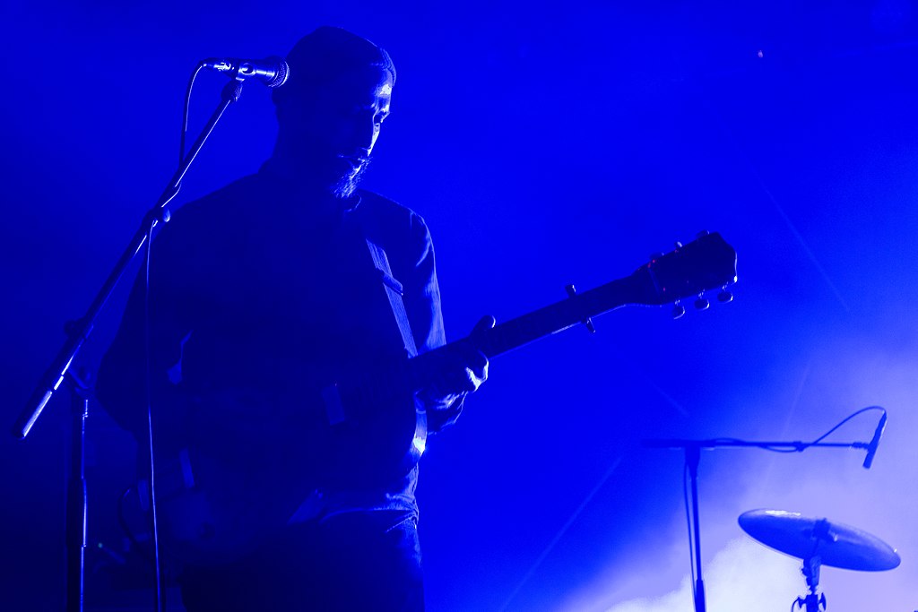 Jawjar at Les Trans Music Festival in Rennes with blue background and tint and one man playing his guitar on stage