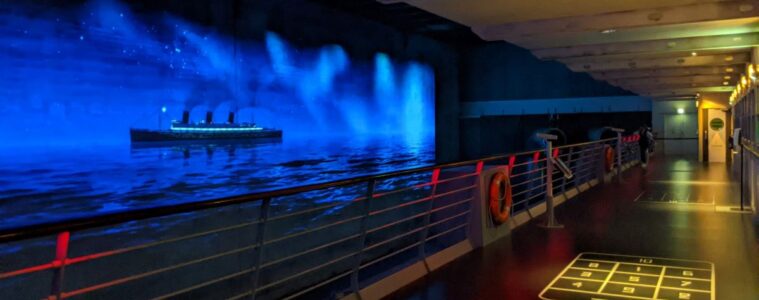 Escal'Atlantic on deck showing darkened deck and video of large passenger ship passing nearby