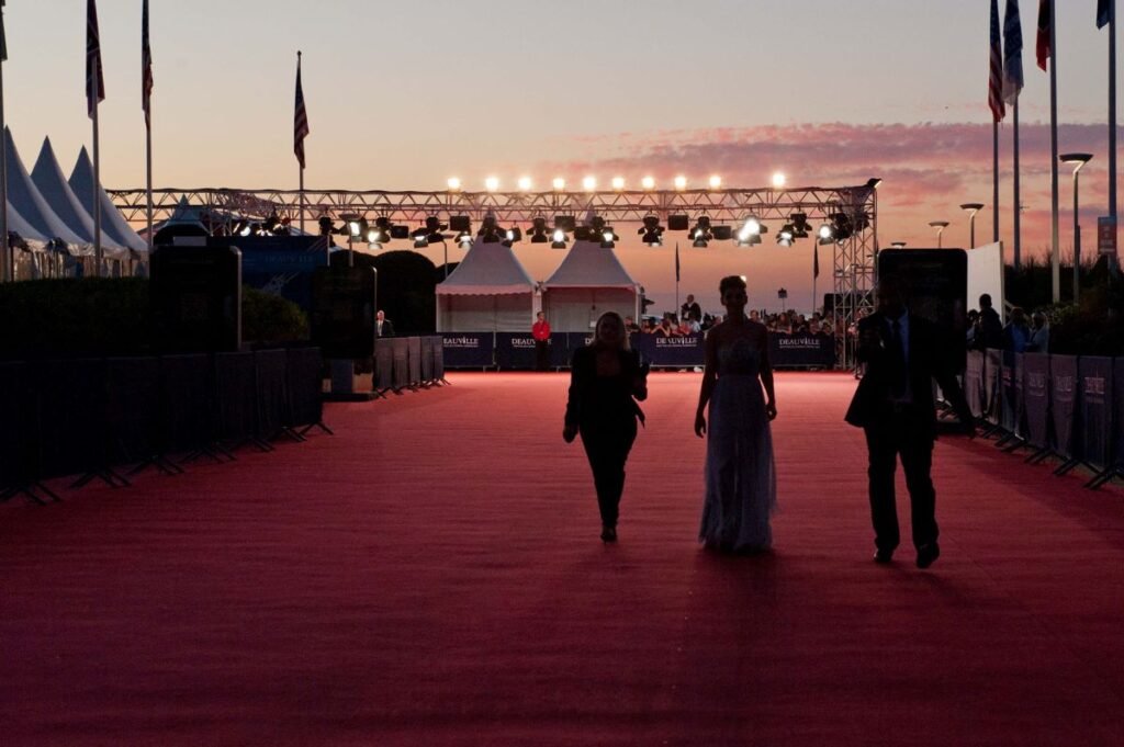 American Film Festival Deauville in evening with three people walking away from camera towards white marquees with lights in distance