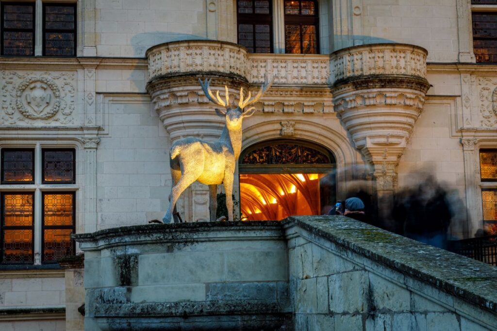 Statue of deer outside Chenonceau lit up with lights in hallway behind
