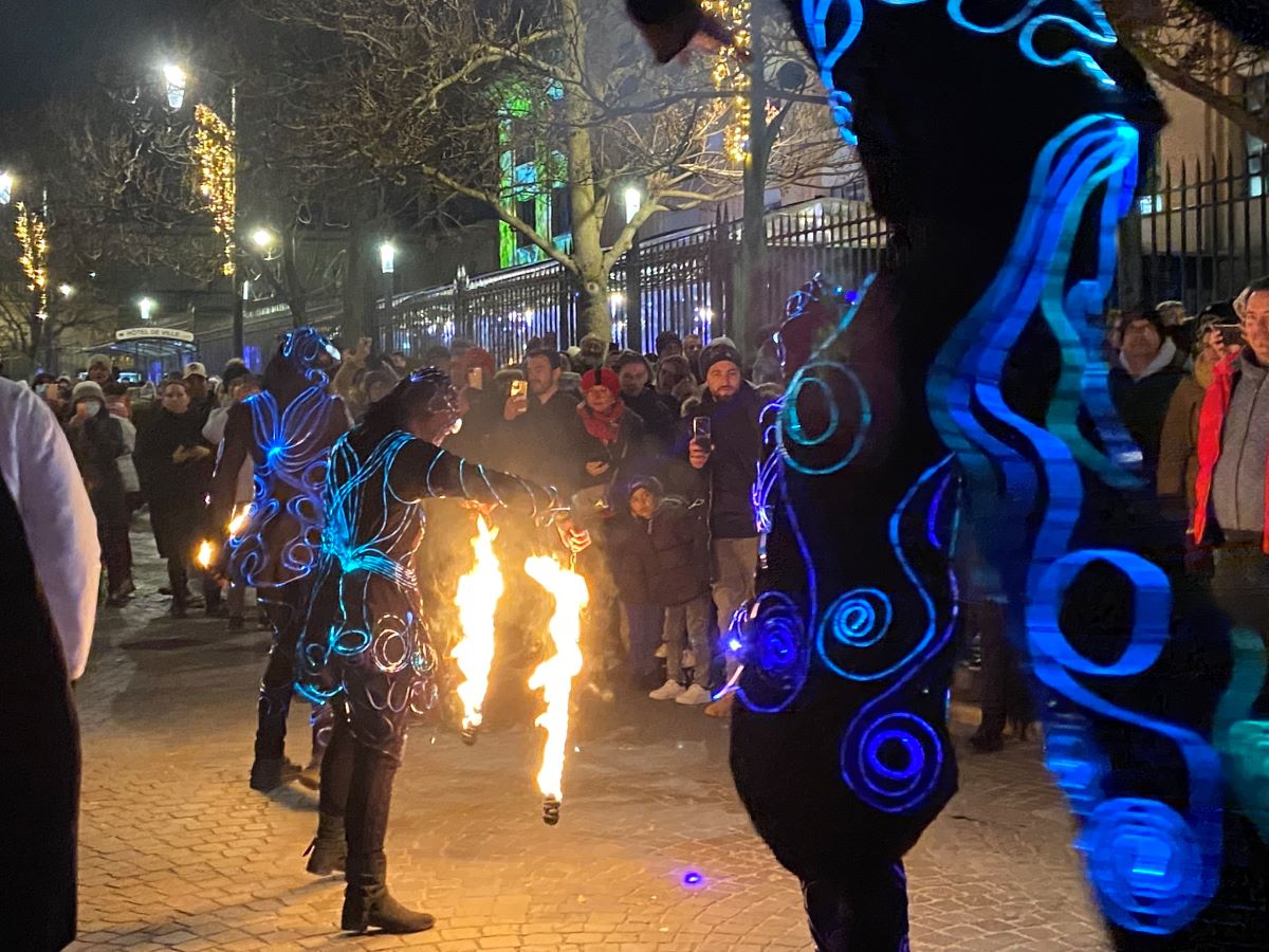 procession in street at Les Habits de Lumiere festival in epernay with figures dressed in weird blue costumes and fire on ground