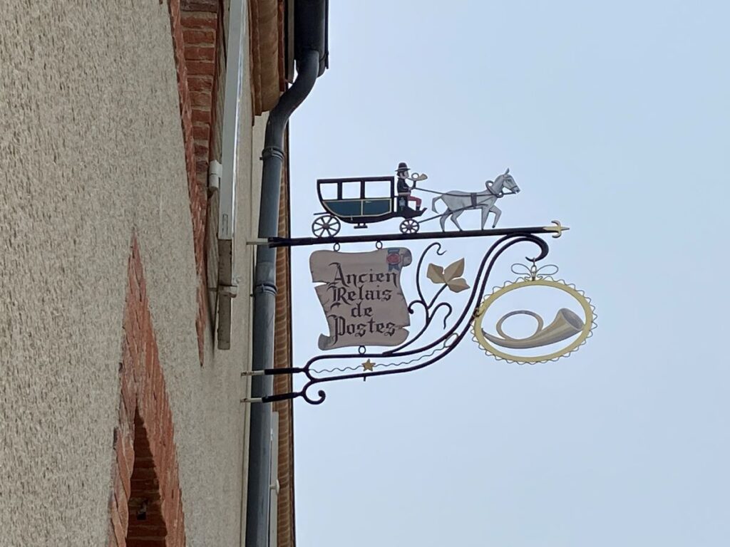 Wrought iron sign in Hautvillers Champagne showing horse and carriage on bar above sign of Auberge