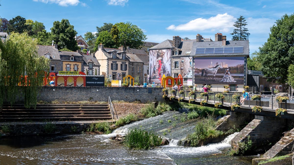La Gacilly 2022 Photo outdoor festival with river in front and bridge and behind old houses and buildings covered in huge photos