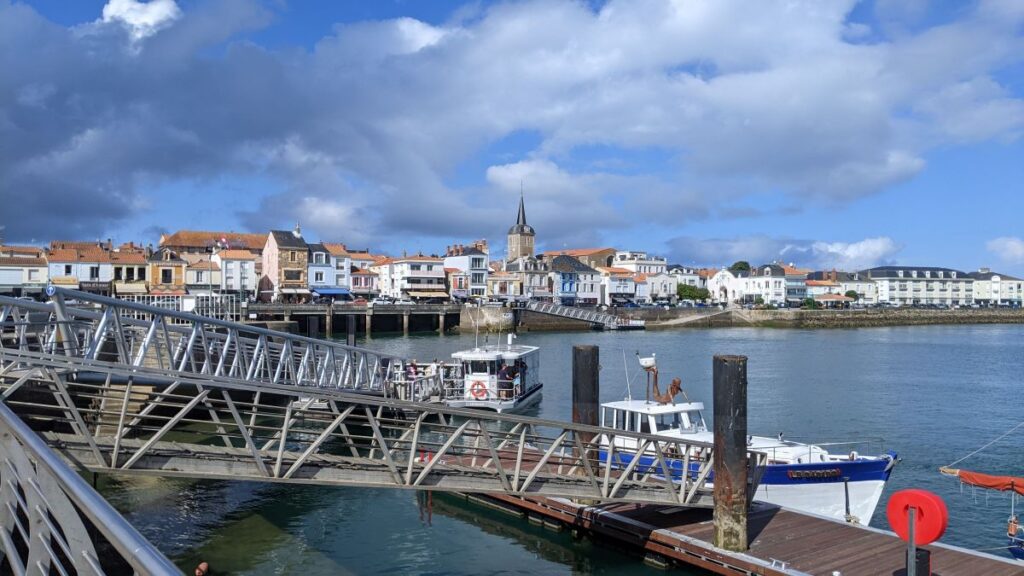 Water ferry boat in Les Sables d'Olonne showing gangway descending from quay to waiting water ferry on water with town in background