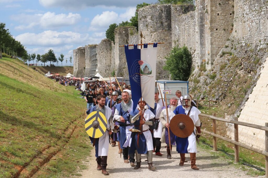 Provins medieval fair with people in costumesmarching in long procession alonb outside of huge city walls