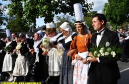Cornwall Festival, Brittany with ladies in big ats and traditional costumes of long skirts and aprons and men in dark costumes walking in line in street